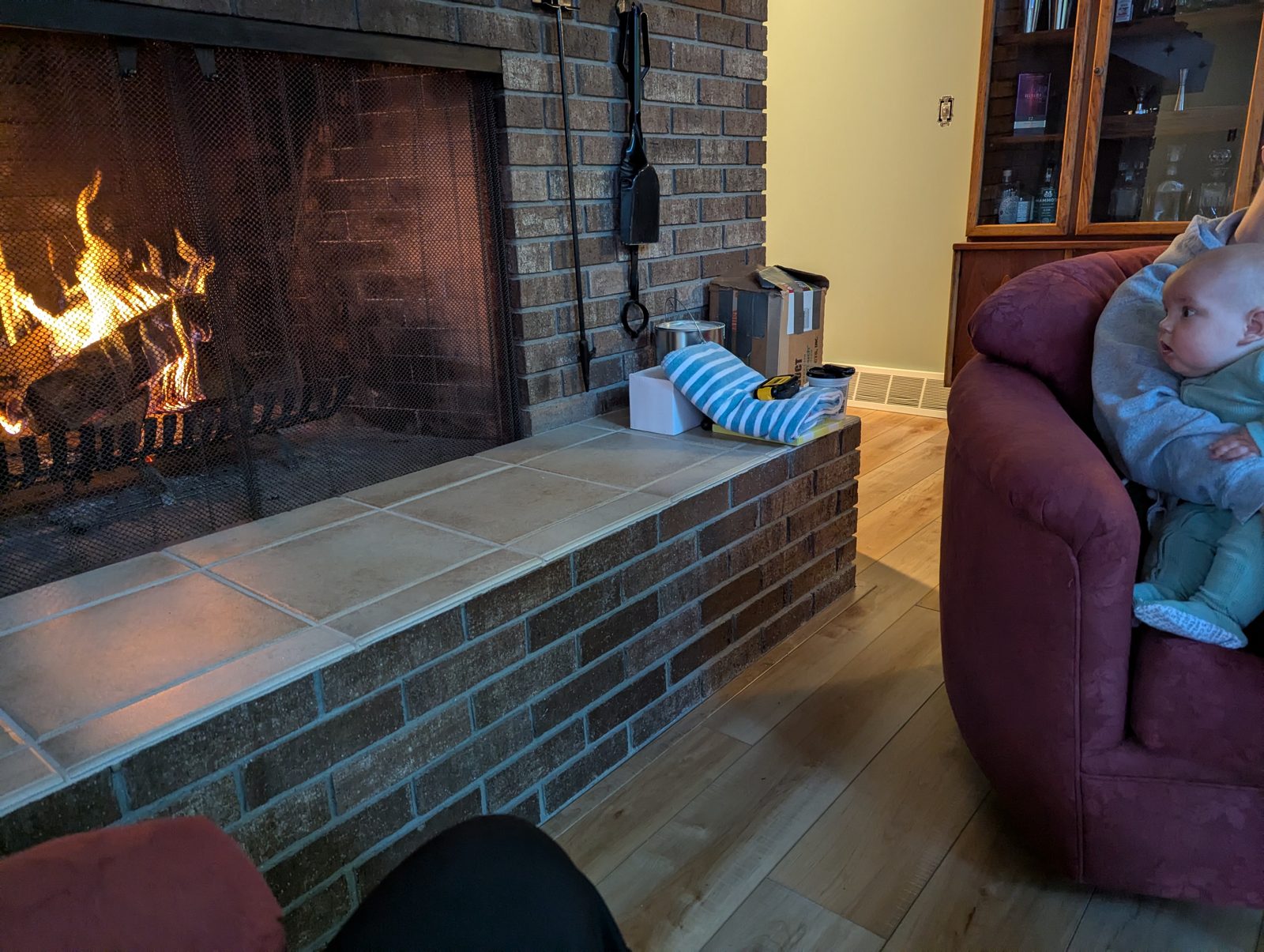 Fireplace burning with a baby sitting on the couch in the background